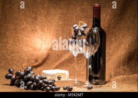 Una bottiglia di vino rosso con gli occhiali e formaggio Foto Stock