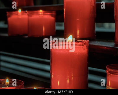 Candele accese in bicchieri di rosso nel buio Foto Stock
