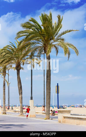 VALENCIA, Spagna - 25 Aprile 2014: Little Boy gioca palla ai piedi delle grandi palme sulla spiaggia di sabbia della città Foto Stock