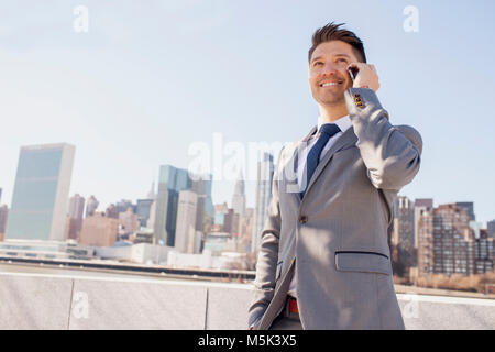 Ritratto di giovane uomo d affari in ambiente urabn parlando sullo smartphone Foto Stock