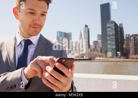 Ritratto di giovane uomo d affari in ambiente urabn la digitazione sullo smartphone Foto Stock