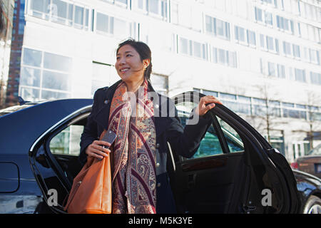 Giovani asiatici business donna uscendo di auto di servizio limousine Foto Stock