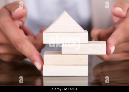 Close-up di imprenditrice rimuovere il blocco di legno da modello di casa sul tavolo Foto Stock