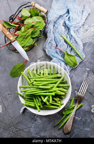 Fagioli verdi nella ciotola e foglie fresche di mangold Foto Stock