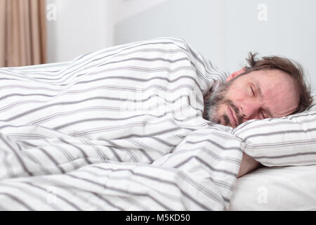 Uomo maturo dormire nel suo letto Foto Stock