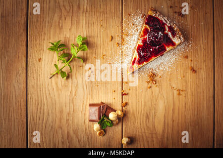 Bella italiana tradizionale cheesecake con frutti rossi, menta e zucchero a velo su sfondo di legno, fuoco selettivo Foto Stock
