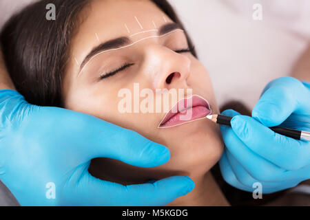 Cosmetologo applicare trucco permanente sul giovane donna di labbra Foto Stock