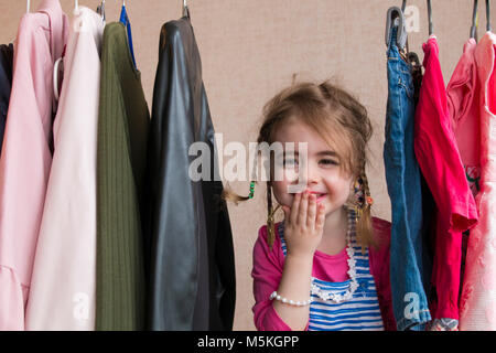 Chiusa-up ritratto di allegro bambina scegliendo i vestiti Foto Stock