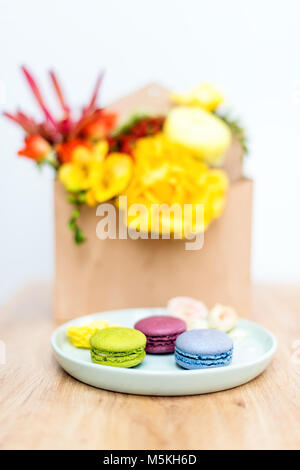 Giftbox con fiori e dolci. Gli amaretti e bouquet di primavera in una scatola di legno. Foto Stock