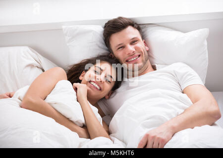 Ritratto di sorridente Coppia Giovane sdraiato sul letto Foto Stock