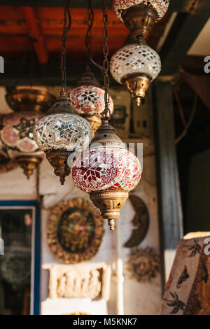 Molte belle vetro lanterne in metallo appendere sullo sfondo di offuscata elementi decorativi. Lanterne Foto Stock