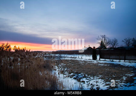 Sunrise contro ortodossi sourenden monastero dai campi congelato, canne e nevoso al di fuori a est della Polonia vicino ai confini Bielarus Foto Stock