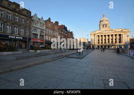 Nottingham, Inghilterra - Febbraio 24, 2018: turisti shopping presso i negozi sulla Piazza del Mercato Vecchio con la Casa del Consiglio durante la primavera. Foto Stock