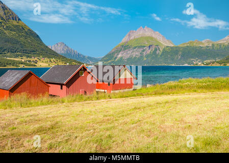 Splendido paesaggio della Norvegia. Red fienili, lago e prati, delle montagne e del cielo molto nuvoloso in background. Viaggiare in Scandinavia, Europa Foto Stock