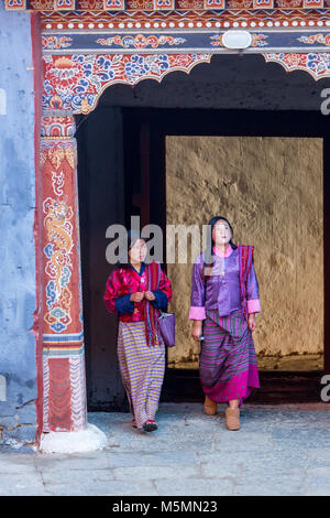 Trongsa, Bhutan. Due donne in abito tradizionale entrando nel primo cortile del Trongsa Dzong (Monastery-Fortress), visto dall'interno della Corte. Foto Stock