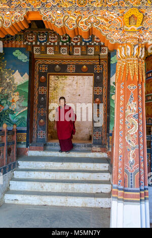 Trongsa, Bhutan. Giovane monaco buddista (accolito) che fuoriesce da un cortile interno in Trongsa Dzong (Monastery-Fortress). Foto Stock