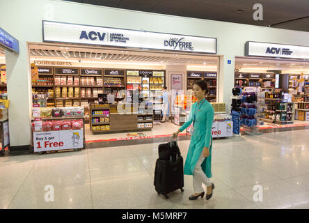 Un hostess aria oltrepassando il Duty Free shop, Ho Chi Minh airport ( l'Aeroporto Internazionale di Tan Son Nhat ), Vietnam Asia Foto Stock