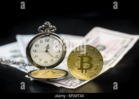 Golden bitcoin e orologio da tasca sul dollaro USA in piedi su sfondo scuro Foto Stock