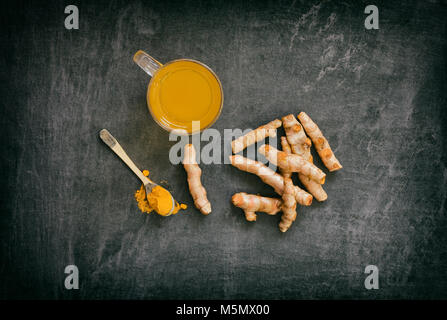 Curcuma longa. Curcuma tè con polvere e rizomi su un sfondo di ardesia. Foto Stock