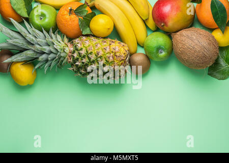 Varietà di differenti e tropicali Frutta estiva. Ananas Manghi Agrumi Noce di Cocco Arance Limoni Mele Kiwi banane disposte a bordo sul turchese Bac Foto Stock