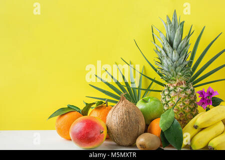 Composizione dalla varietà di differenti e tropicali Frutta estiva. Ananas Manghi Agrumi Noce di Cocco Arance Limoni Mele Kiwi banane disposti su pietra Foto Stock