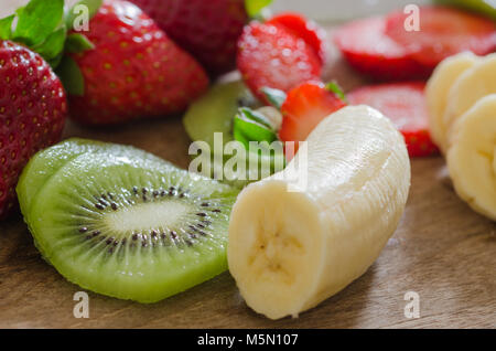 Sbucciate le banane e le fragole tagliate su un pavimento di legno Foto Stock