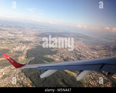 L'ala di Helvetic Airways aeroplano sopra la città di Zurigo in Svizzera Foto Stock