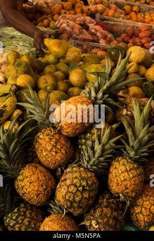 Pressione di stallo di frutta con una mano prendendo un po' di frutta lontano dal display in un mercato in Colombia. Foto Stock