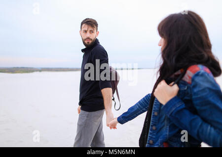 Ragazza e ragazzo passeggiate in riva al mare a cercare posto f Foto Stock