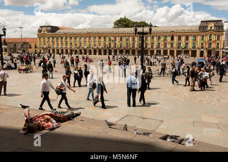 Plaza de Simon Bolivar a Bogotà, in Colombia con gli edifici del governo e la gente camminare e vagrant giacenti sui passi in primo piano Foto Stock