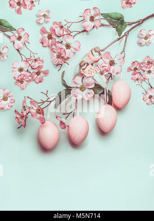 La pasqua di rosa pastello con layout impiccato uova e il decor blossom su sfondo turchese Foto Stock
