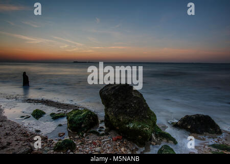 Al tramonto o sun verso il basso sopra la spiaggia sulla costa dell'isola di Wight. seascape atmosferica o panorama al tramonto con rocce al mare. atmosferica. Foto Stock