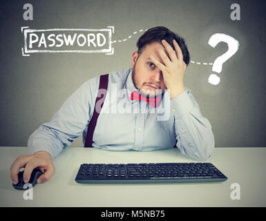 Disperata giovane uomo che cerca di accedere al suo computer password dimenticata Foto Stock