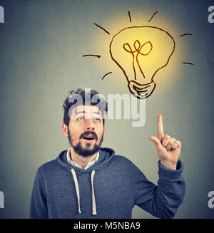 Casual uomo barbuto in hoodie rivolta verso l'alto illuminismo con grande idea. Foto Stock