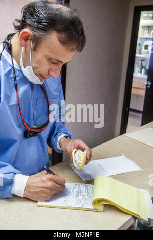 Miami Beach Florida,41st Street,dentista,medicina dentale,maschio ispanico,professionista della salute,denti,maschera chirurgica,scrub,impressione,scrittura,muffa,falsa tee Foto Stock