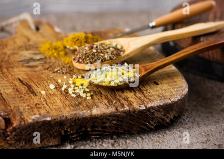 Diverse spezie a secco in cucchiai sulla tavola di legno sfondo Foto Stock