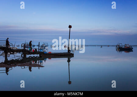 Due pescatore in attesa per la barca a raccoglierli dal molo a Felixstowe Ferry in Suffolk, Inghilterra. Foto Stock