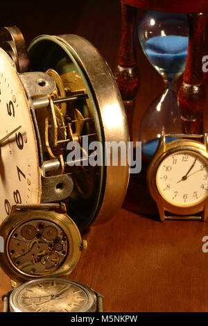Clessidra, vecchio orologio e meccanismo di orologio su sfondo di legno Foto Stock