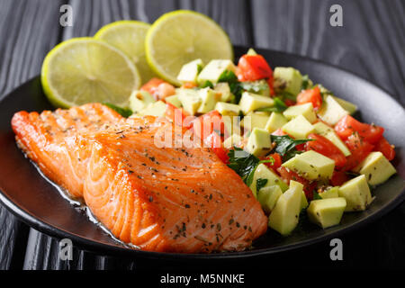 Fritto bistecca di salmone con avocado salsa di pomodoro closeup su una piastra orizzontale. Foto Stock