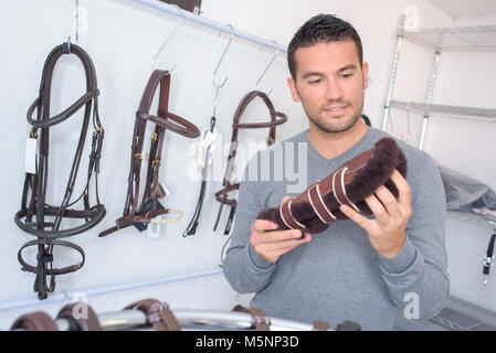 Uomo che guarda un parastinchi in un negozio equestre Foto Stock