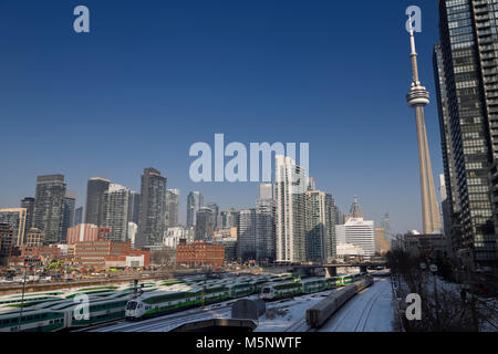 Vai " commuter " treni e via treno sulle vie della Union Station di Toronto, la CN Tower e cityscape skyline di highrise edifici Foto Stock