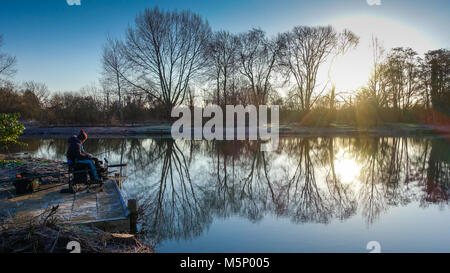 Ponte Henlow laghi, Henlow, Bedfordshire, 25 febbraio 2018. Una Carpa pescatore braves sub zero temps su un nitido, soleggiato, inverno mattina con temperature meteo a scendere a meno 5 gradi Celsius. Credito: Mick Flynn/Alamy Live News Foto Stock