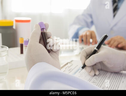 Medico tenendo una bottiglia del campione di sangue in laboratorio. scienza e concetto medico Foto Stock