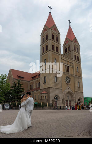 Un giovane cinese comporta per le loro foto di nozze presso il famoso St. Michael's Cathedral di Qingdao. Foto Stock