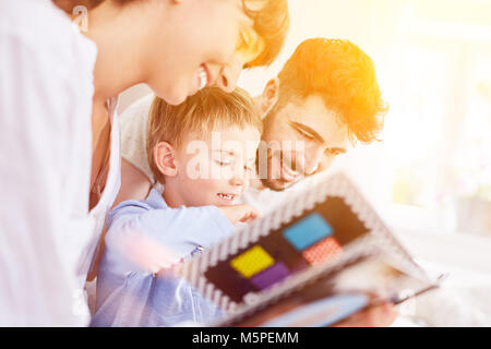 Famiglia guarda foto o album picture book con il figlio a casa Foto Stock