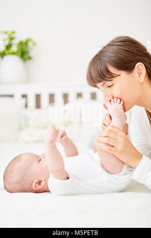 Felice madre teneramente coccole con il suo neonato a casa Foto Stock