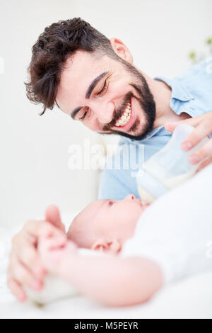 Amare e felice padre nutre il suo bambino con il latte dalla bottiglia Foto Stock