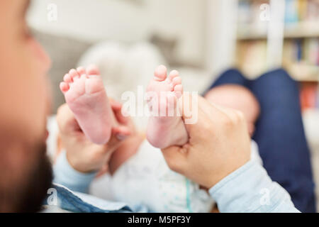 Padre tiene il piccolo piedi del suo neonato Foto Stock