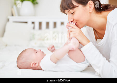 Amorevole Madre teneramente baci i piedi del suo neonato Foto Stock