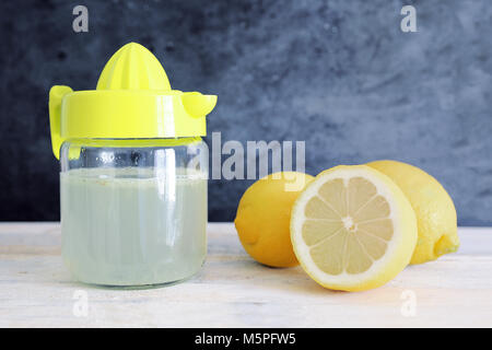 Succo di limone appena spremuto su un tavolo di legno. Spazio di copia vuoto per il testo dell'editor. Foto Stock